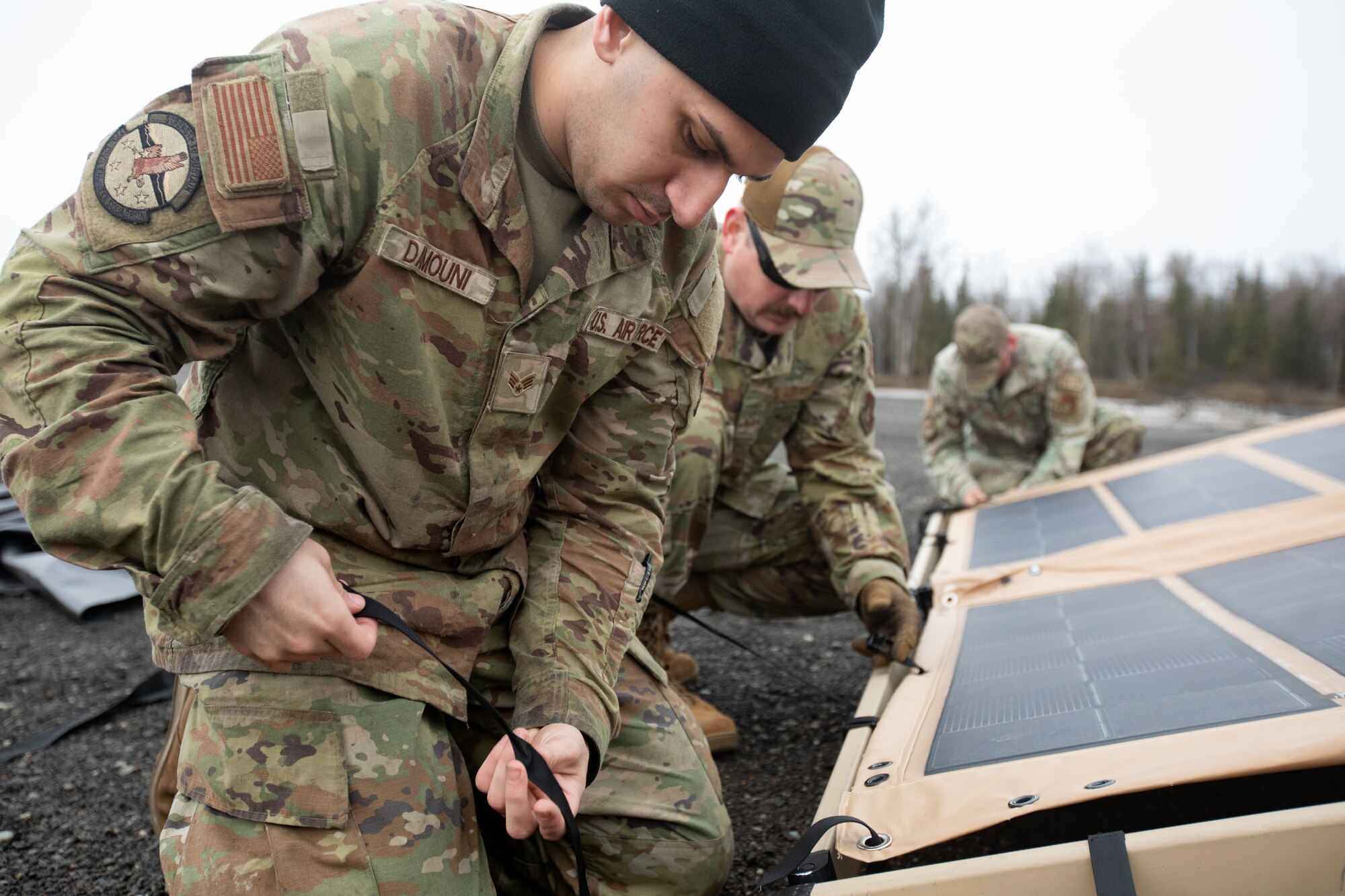 U.S. Air Force Senior Airman John Damouni, left, a water and fuel systems maintenance journeyman assigned to 773rd Civil Engineer Squadron, secures solar panels to an air transportable clinic tent at Camp Mad Bull, during Northern Edge 23-1, at Joint Base Elmendorf-Richardson, Alaska, May 9, 2023.