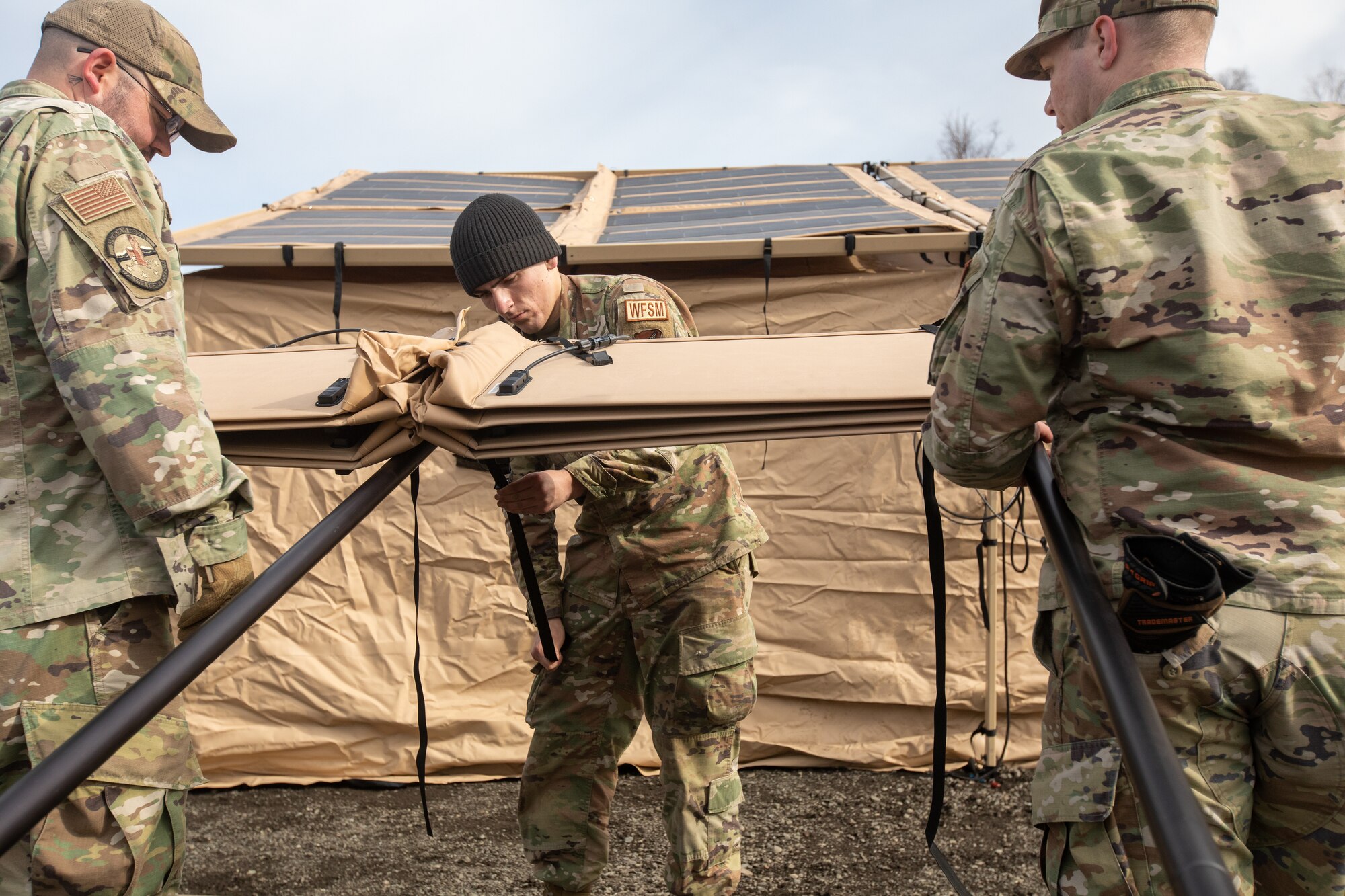 U.S. Air Force  Tech. Sgt. Austin Myers, left, Airman 1st Class Christopher Wolverton, center, and Airman 1st Class Matthew Jaeger, right, water and fuel systems maintenance personnel assigned to 773rd Civil Engineer Squadron, set up a solar panel system for an Agile Combat Employment tent air transportable clinic, during Northern Edge 23-1 at Joint Base Elmendorf-Richardson, Alaska, May 9,