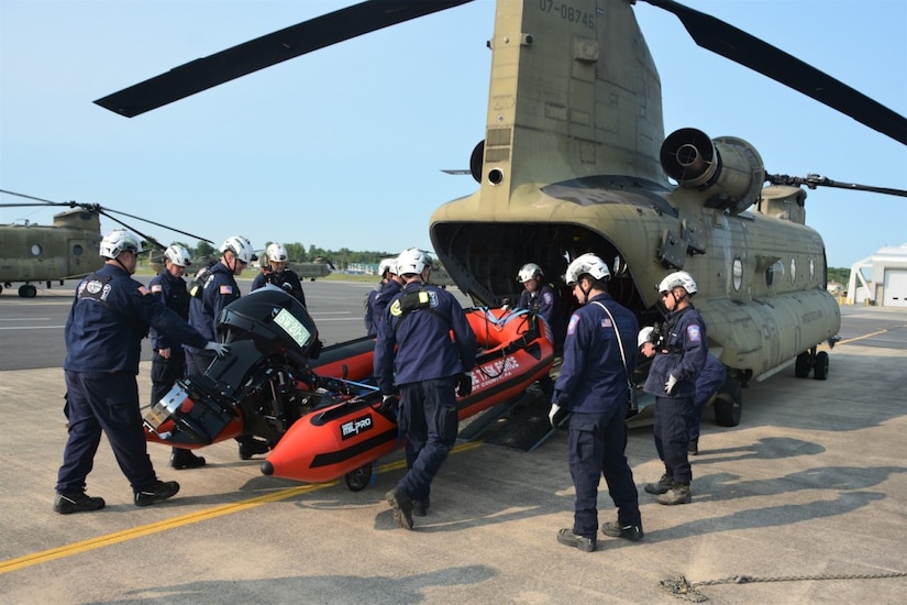 Search and rescue personnel load a rubber boat into an aircraft.