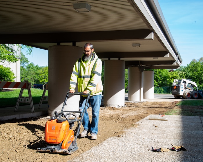 Man prepares ground for sidewalk.