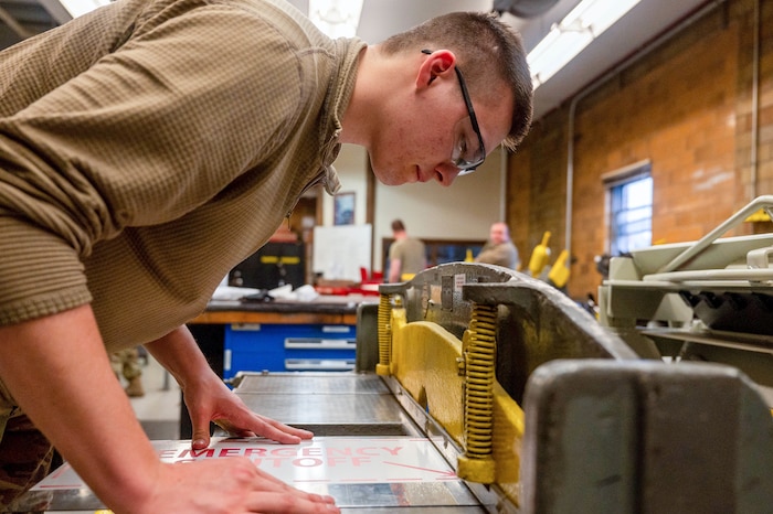 Staff Sgt. Matthew Tormanen, 934th Maintenance Squadron aircraft structural maintenance technician, cuts some sheet metal to size for a sign, May 6, 2023, at the Minneapolis-Saint Paul Air Reserve Station, Minnesota. This machine ensures a straight edge is cut through sheet metal and is operated by a foot pedal.(U.S. Air Force photo by Senior Airman Colten Tessness)