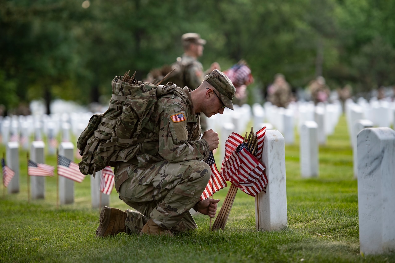 Soldiers place flags on headstones.