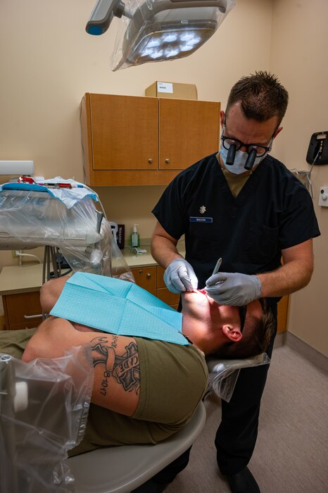 U.S. Air Force Lt. Col. Jared Mason, 5th Medical Group dentist, examines a patient's mouth during a routine dental check-up at Minot Air Force Base, North Dakota, April 27, 2023. The Air Force Dental Service’s mission is to provide innovative, expeditionary Airmen and Guardians to support global operations and ensure a dentally fit force through trusted care. (U.S. Air Force photo by Airman 1st Class Nottingham)