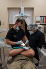 U.S. Air Force Lt. Col. Jared Mason, 5th Medical Group dentist, and Senior Airman Thalia Morales-Diaz, 5th Medical Group dental technician, examine a patient's mouth during a routine dental check-up at Minot Air Force base, North Dakota, April 27, 2023. Dental technicians are responsible for aiding in every part of the practice from simple exams and taking x-rays to assisting in oral surgery. (U.S. Air Force photo by Airman 1st Class Nottingham)