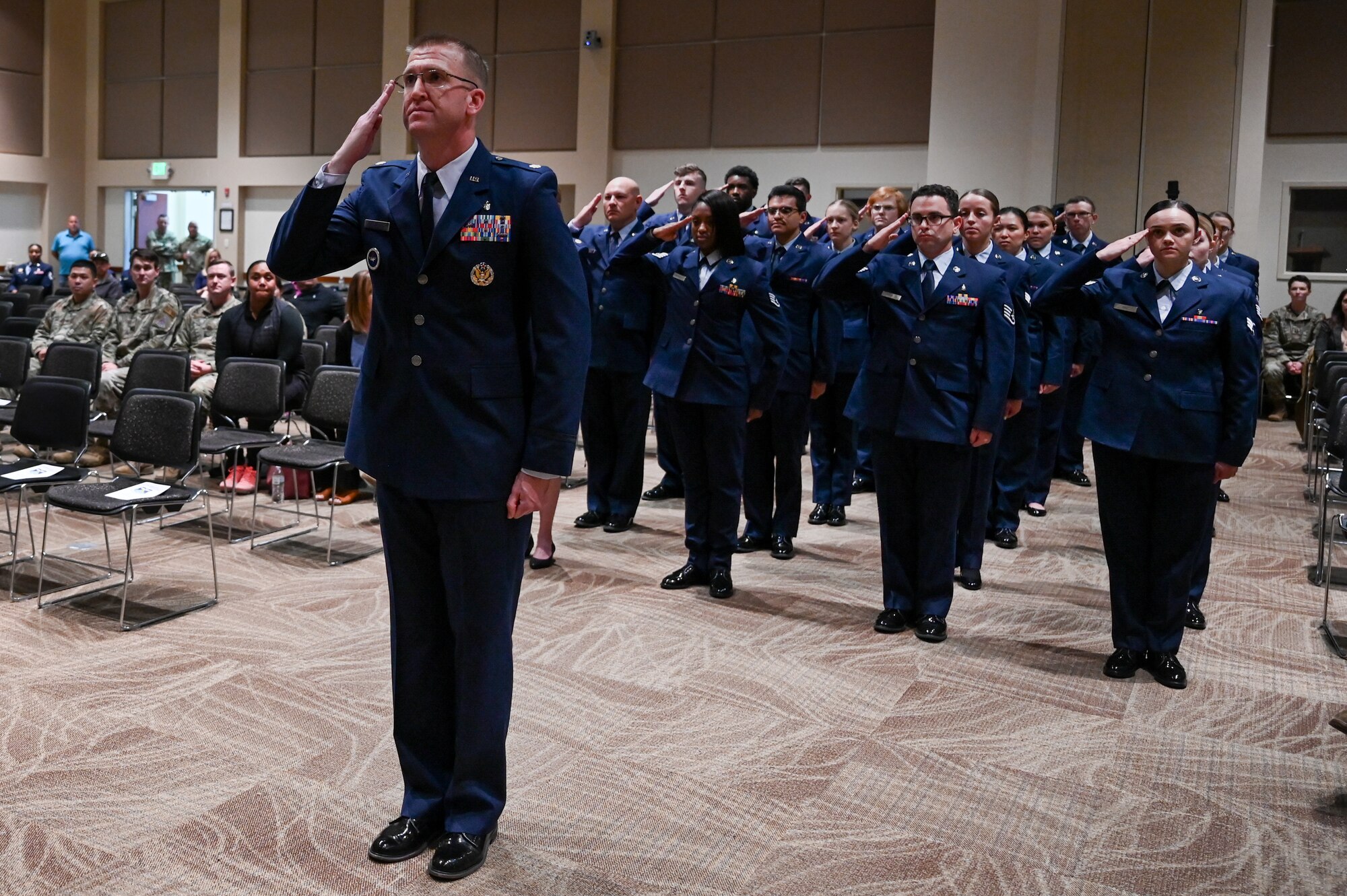 Service members stand and salute in formation