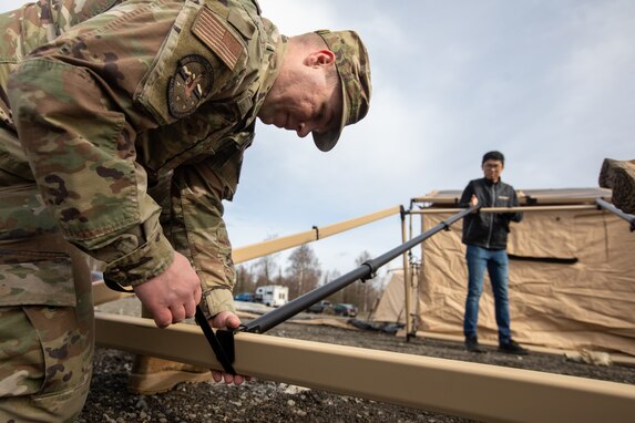U.S. Air Force Airman 1st Class Matthew Jaeger,  a water and fuel systems maintenance journeyman, left, assigned to 773rd Civil Engineer Squadron and defense contractor and electrical engineer Raymond Choy, assemble rafters for Agile Combat Employment air transportable clinic tents during Northern Edge 23-1 at Joint Base Elmendorf-Richardson, Alaska, May 9, 2023.