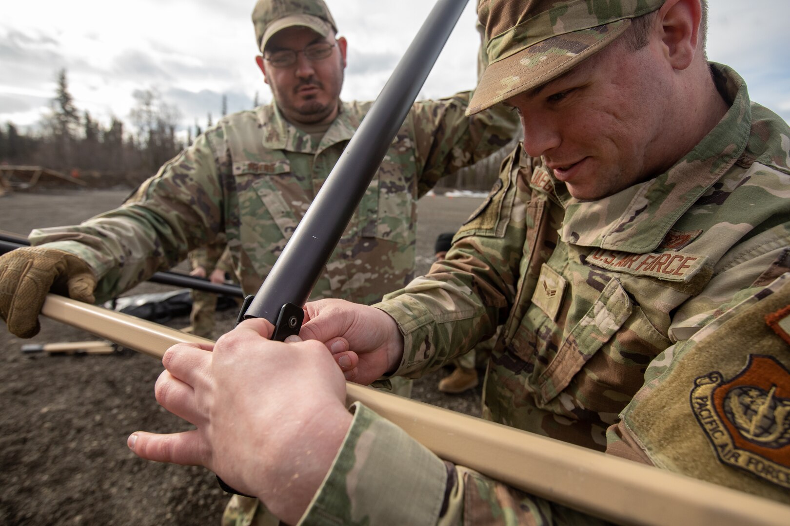 U.S. Air Force Airman 1st Class Matthew Jaeger, a water and fuel systems maintenance journeyman, right, and Tech. Sgt. Austin Myers, a water and fuel systems maintenance supervisor, left, both assigned to 773rd Civil Engineer Squadron, assemble rafters for an Agile Combat Employment air transportable clinic, during Northern Edge 23-1 at Joint Base Elmendorf-Richardson, Alaska, May 9, 2023.