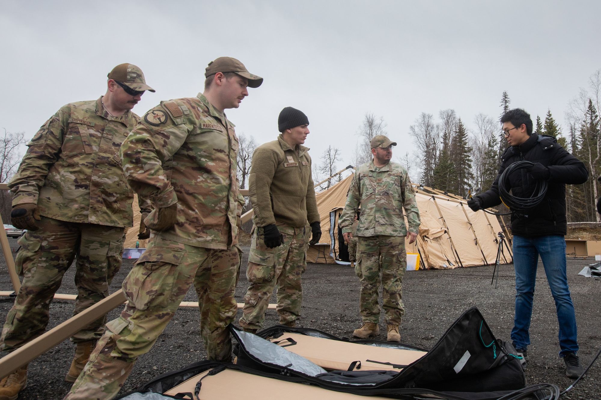 Electrical Engineer and defense contractor Raymond Choy, right, instructs members of the 773rd Civil Engineer Squadron how to wire the solar system for an Agile Combat Employment air transportable clinic at Camp Mad Bull, during Northern Edge 23-1 at Joint Base Elmendorf-Richardson, Alaska, May 9, 2023.