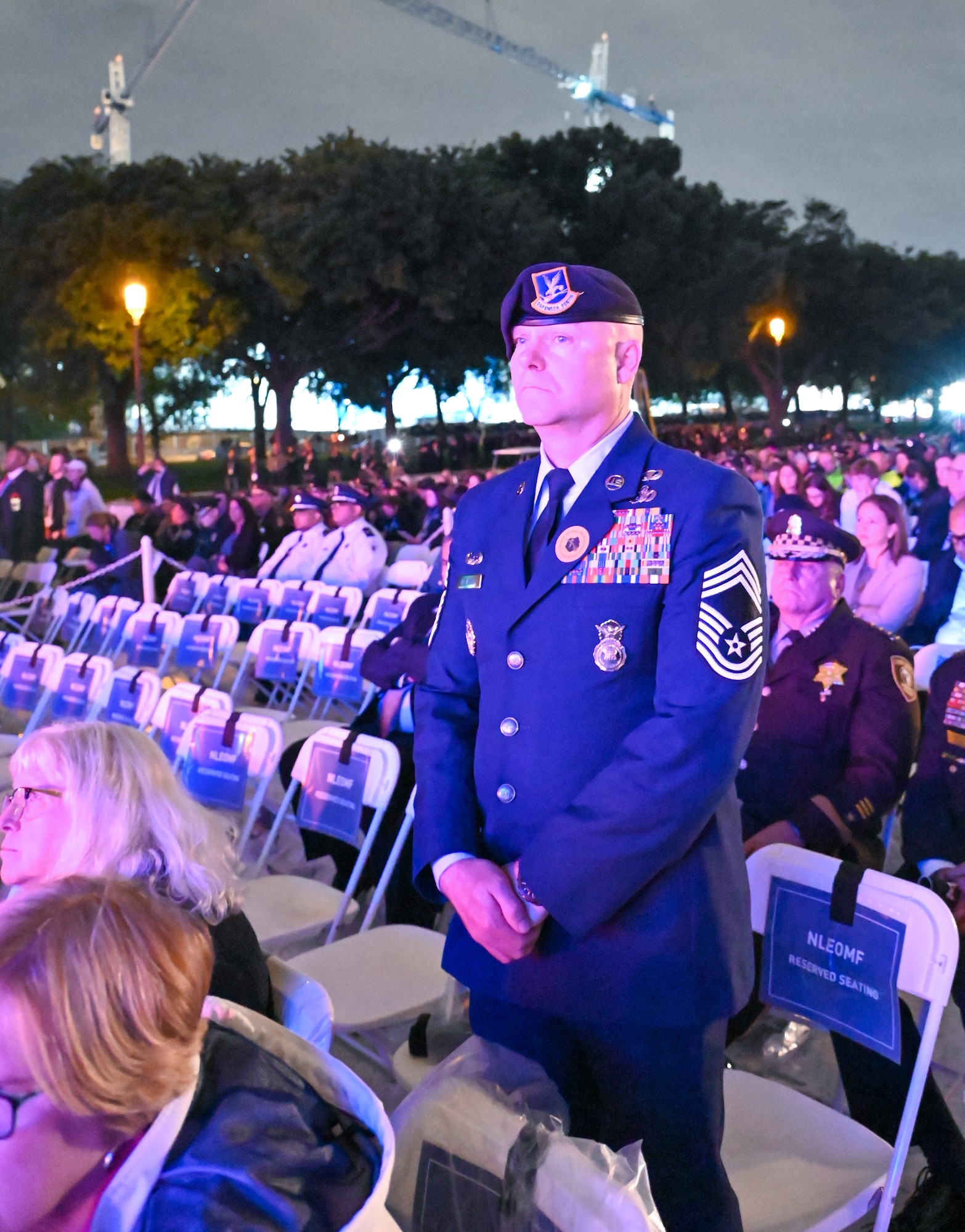 An Air Force chief master sergeant stands to pay tribute to Air Force security forces members whose names were read during a roll call at the 35th annual candlelight vigil at the National Mall in Washington, D.C. May 13, 2023. The vigil recognized law enforcement officers killed in the line of duty whose names were dedicated on the U.S. National Law Enforcement Memorial in Washington, D.C. Five hundred and fifty-six names were read aloud in front of a crowd of thousands. (U.S. Air Force photo by Abigail Meyer)