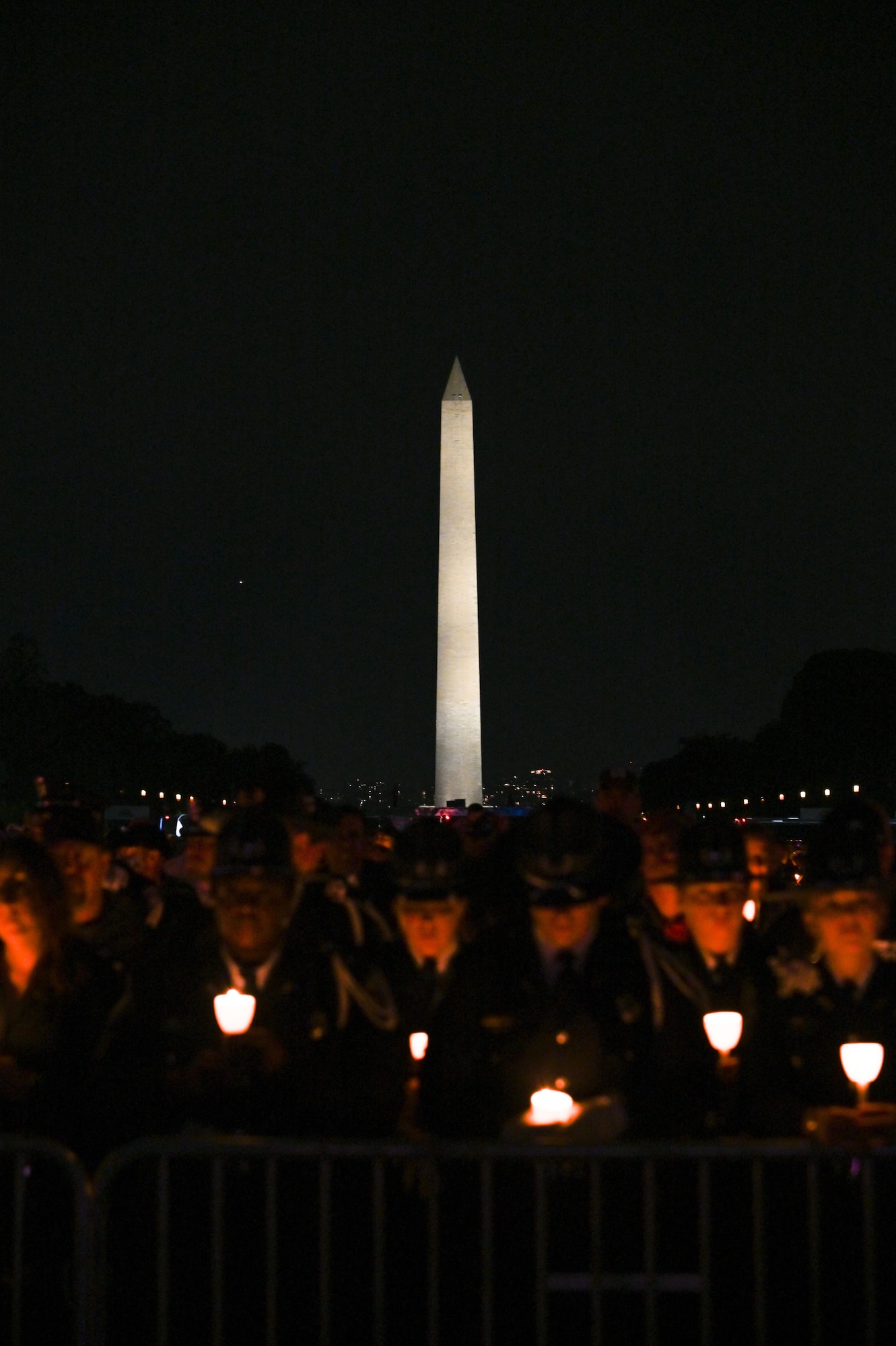 Law enforcement officers from across the country hold candles to pay tribute to law enforcement officers who were killed in the line of duty during a candlelight vigil on the National Mall in Washington, D.C. May 13, 2023. After a long process of gathering the information, routing, and submitting the two fallen Airmen, they were finally approved to be added to the memorial. Their names were then engraved on the memorial and read at the 35th Annual Candlelight Vigil during National Police Week.  (U.S. Air Force photo by Abigail Meyer)