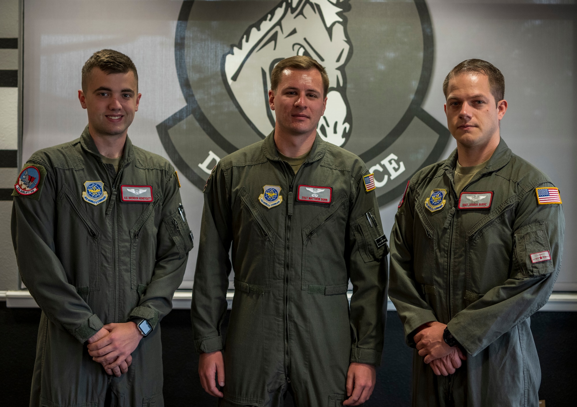 Three Airmen stand shoulder to shoulder.