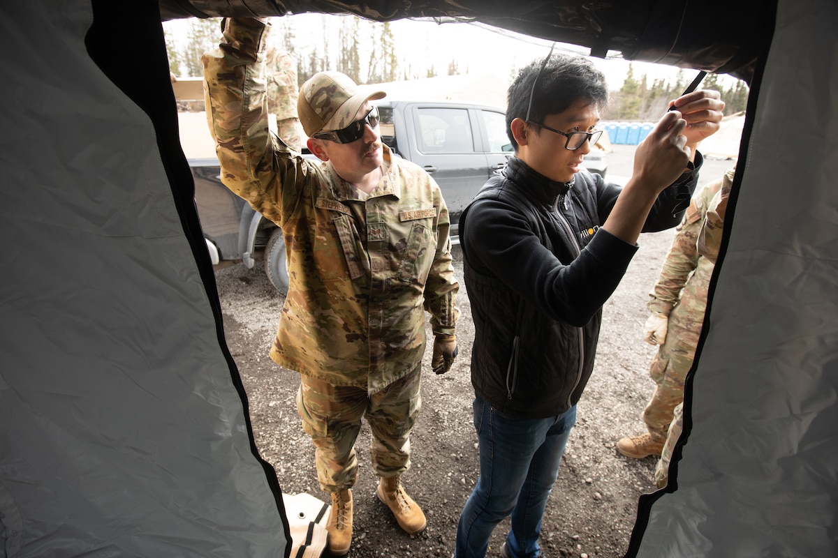 U.S. Air Force Staff Sgt. Gudmundur Stephenson, left, a water and fuel systems maintenance supervisor assigned to 773rd Civil Engineer Squadron, erects a tent with defense contractor and electrical engineer, Raymond Choy, during a Northern Edge 23-1 Agile Combat Employment air transportable clinic set upat Joint Base Elmendorf-Richardson, Alaska, May 9, 2023.