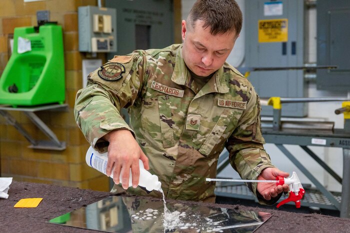 Tech. Sgt. Daniel Richards, 934th Maintenance Squadron aircraft structural maintenance technician, applies soap to sheet metal during a sign fabrication process, at the Minneapolis-Saint Paul Air Reserve Station, Minnesota, May 6, 2023. This cleaning process is to ensure an applied sticker will stay seated.(U.S. Air Force photo by Senior Airman Colten Tessness)