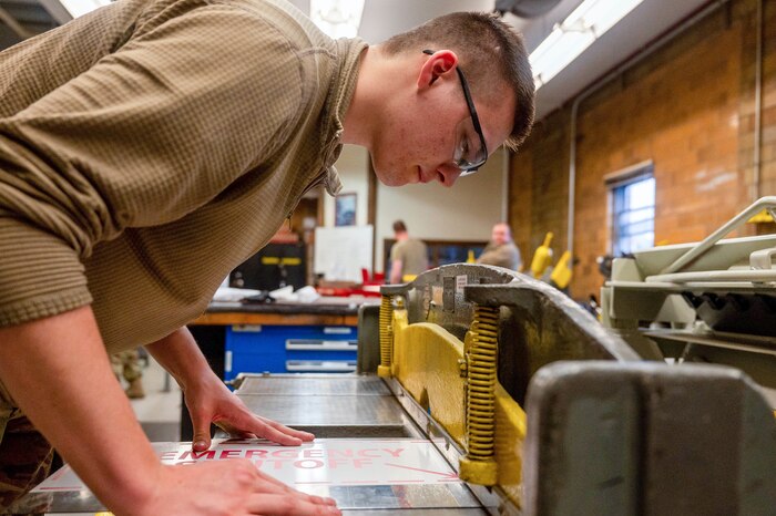 Staff Sgt. Matthew Tormanen, 934th Maintenance Squadron aircraft structural maintenance technician, cuts some sheet metal to size for a sign, May 6, 2023, at the Minneapolis-Saint Paul Air Reserve Station, Minnesota. This machine ensures a straight edge is cut through sheet metal and is operated by a foot pedal.(U.S. Air Force photo by Senior Airman Colten Tessness)