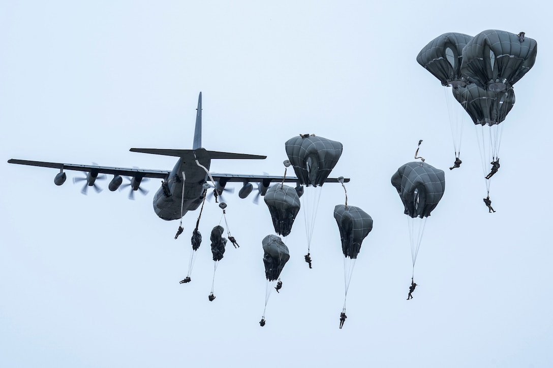 A group of paratroopers jump from a large plane.