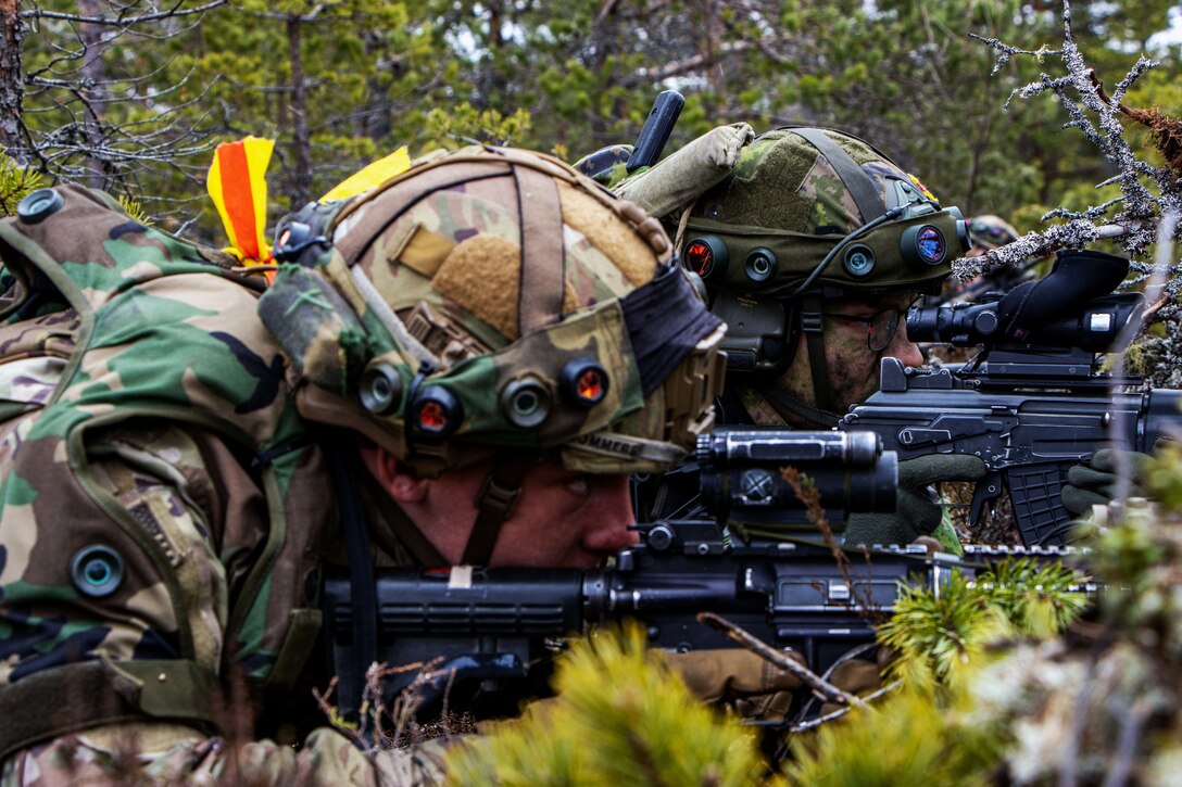 Two soldiers lay on the ground while looking through the sites of their weapons during a training exercise.