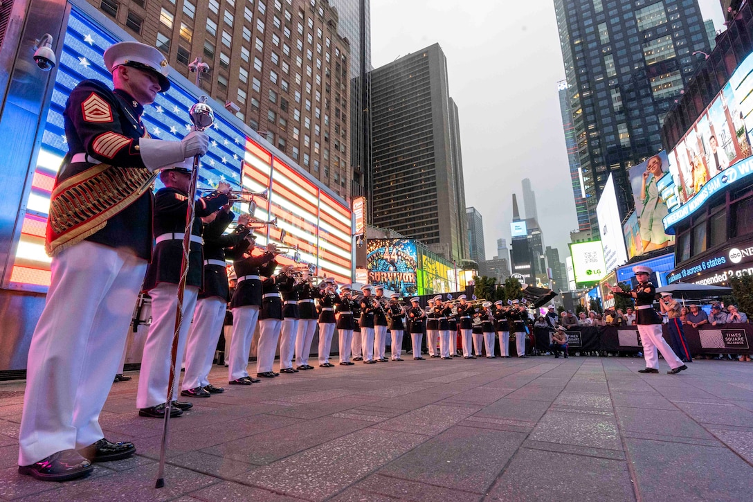 Marines stand in a semicircle playing instruments as a crowd watches.
