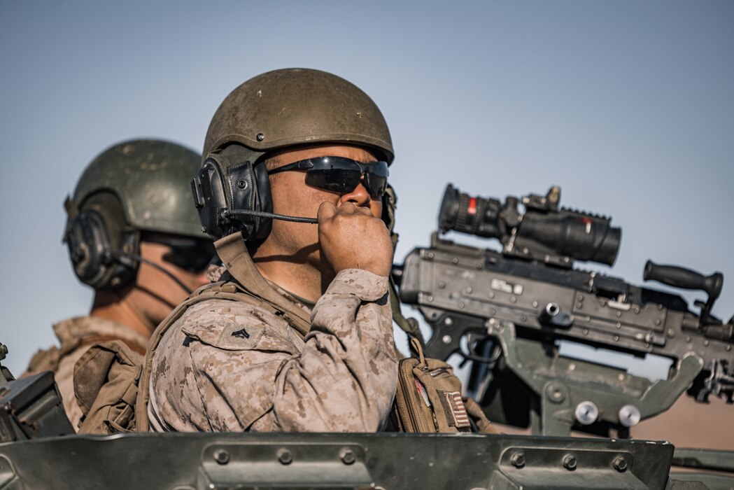 Two U.S. Marines sit atop a military vehicle