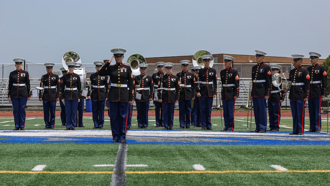 U.S. Marine Corps Gunnery Sgt. Anna H. Henrickson, band director, salutes during the playing of the National Anthem while The Quantico Marine Band stands at attention at Hauppauge High School, Long Island, New York during the first day of Fleet Week New York (FWNY), May 24, 2023. More than 3,000 service members from the Marine Corps, Navy and Coast Guard and our NATO allies from Great Britain, Italy and Canada are engaging in special events throughout New York City and the surrounding Tri-State Region during FWNY 2023, showcasing the latest capabilities of today’s maritime services and connecting with citizens. The events include free public ship tours, military static displays, and live band performances and parades. (U.S. Marine Corps photo by Lance Cpl. David Brandes)
