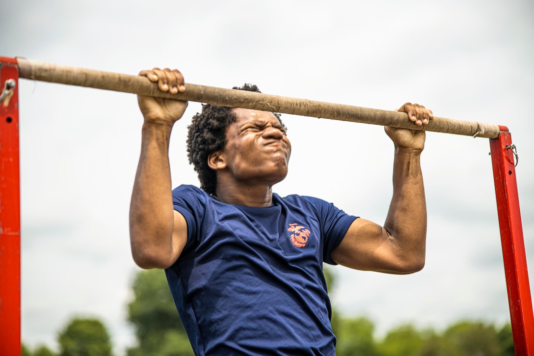 A poolee scrunches their face while performing a pullup.