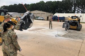 Airmen smooth the surface of concrete in a large hole.