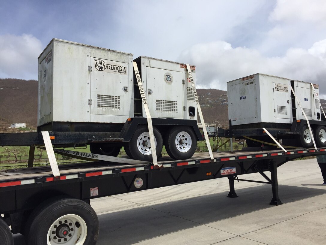 Two white power generators sit on the back of a semi-truck.