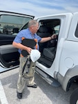 Man putting backpack and sleeping bag in vehicle