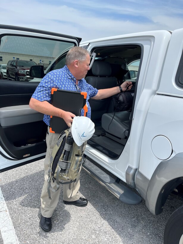 Man putting backpack and sleeping bag in vehicle