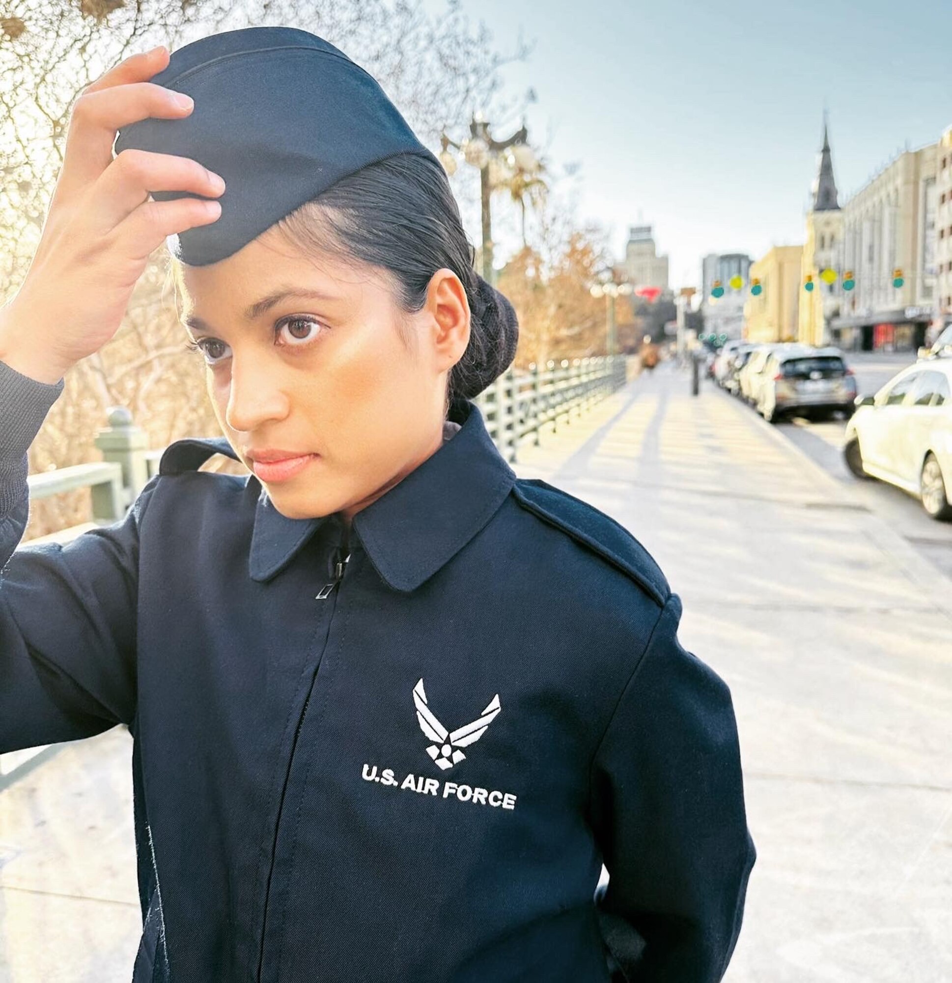 Woman in military uniform standing while fixing her hat
