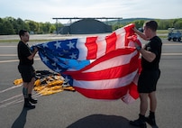 U.S. Army Staff Sgt. Nickolas Orozco and Specialist Brandon Hexum, U.S. Army Golden Knight parachute team demonstrators, prepare the American flag prior to a flight and demonstration during the 2023 Westfield International Air show May 13, 2023, at Barnes Air National Guard Base, Massachusetts. Air shows are a public event held on base to provide an opportunity for people to see U.S. military air capabilities in action and meet the service members who fly and maintain the equipment. (Massachusetts Air National Guard Photo by Tech. Sgt. Kevin R. Nunes)