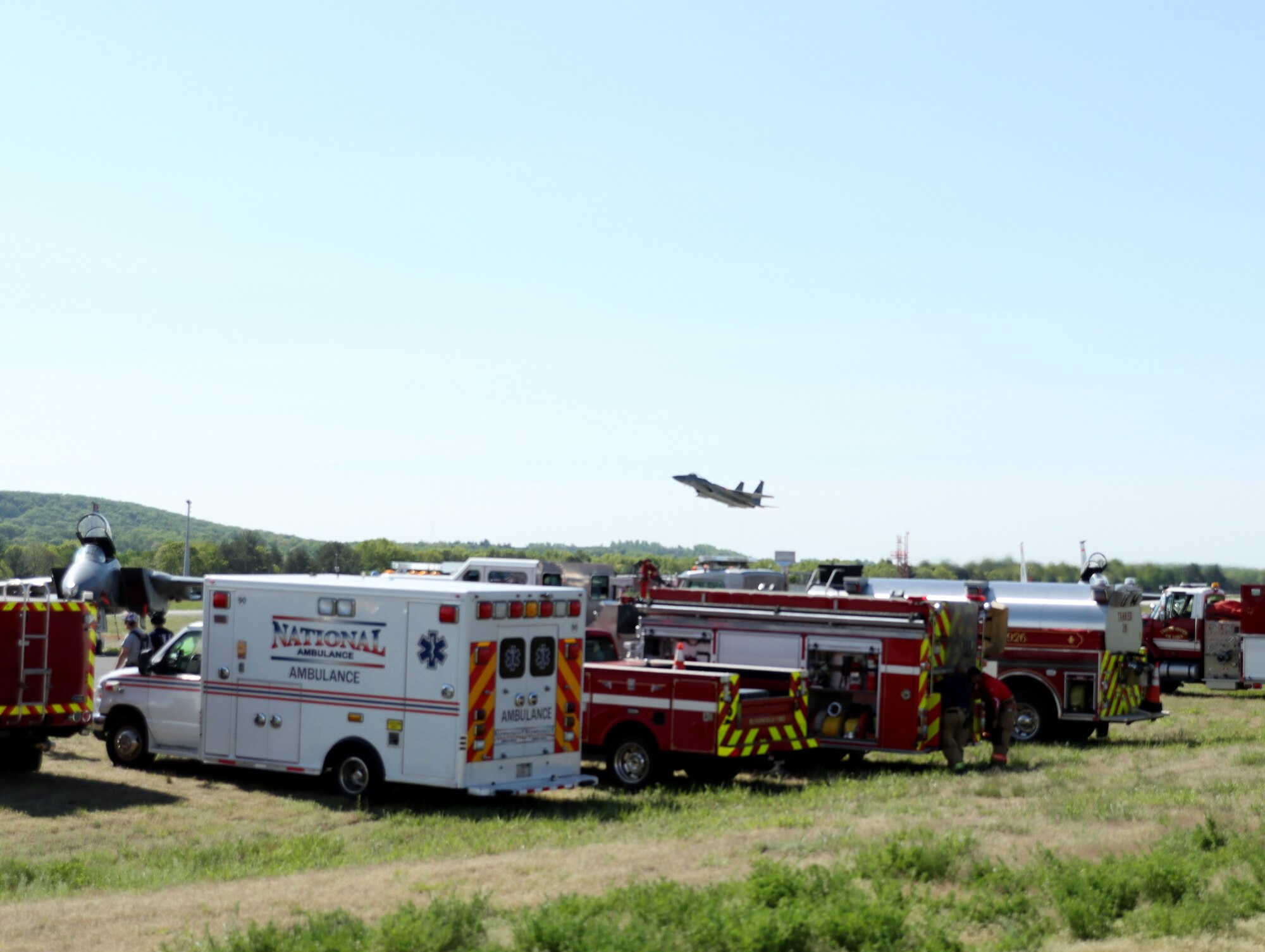 An F-15C Eagle assigned to the 104th Fighter Wing flies over first responders during the 2023 Westfield Air Show, May 13, 2023, at Barnes Air National Guard Base, Massachusetts. Medical personnel were essential to ensure the local community and attendees remained safe during the event. (Courtesy Photo by Aedan Nault-Goodreau)