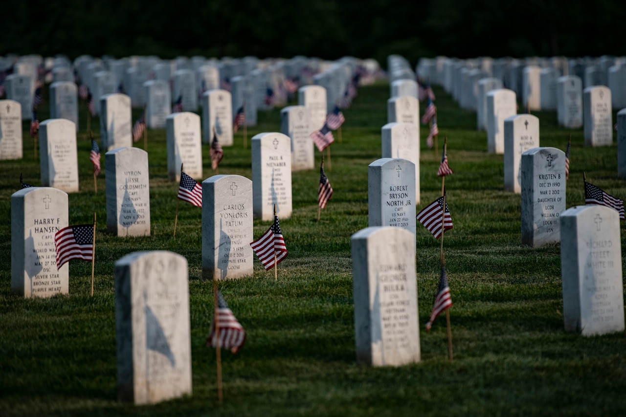 U.S. flags adorn rows of headstones at a cemetery.