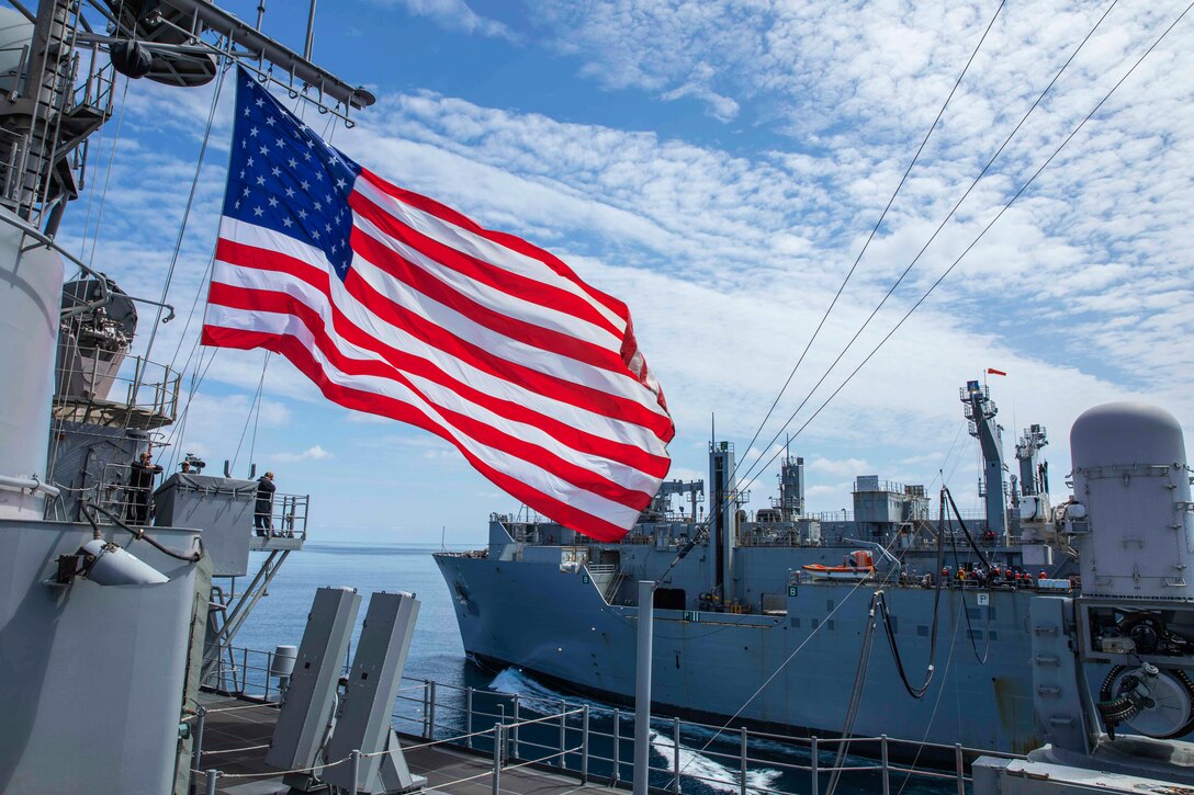 A ship flies the American flag during a replenishment-at-sea.