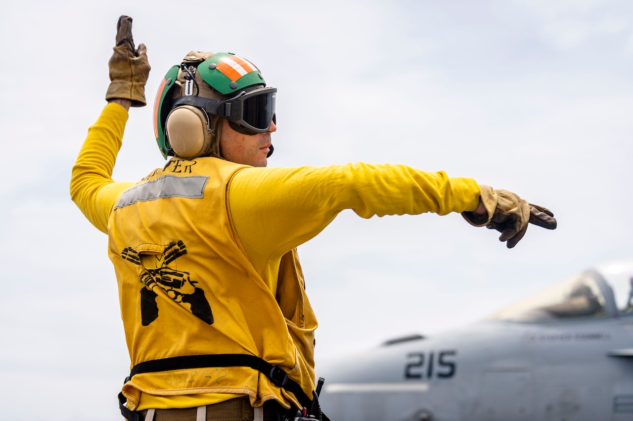 Close-up of a sailor signaling on the deck of a ship.