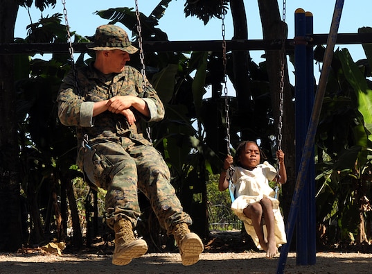 U.S. Marine Corps Lance Cpl. Tyler Woodard, assigned to the 22nd Marine Expeditionary Unit embarked aboard the amphibious assault ship USS Bataan (LHD 5), swings beside a Haitian girl at the Heart to Heart orphanage in Grand Goave, Haiti, Feb. 1, 2010.