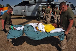 U.S. Marines and Sailors of Combat Logistics Battalion 24, 24th Marine Expeditionary Unit, off-load three Haitian patients from a MH-60 helicopter, Feb. 5, 2010. The patients were transported from the USNS Comfort. (DoD Photo)