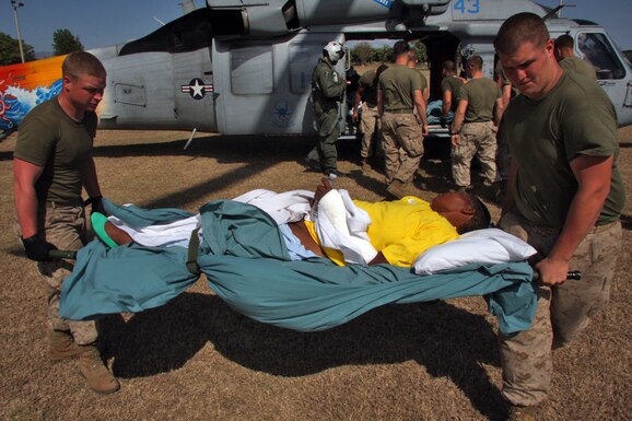 U.S. Marines and Sailors of Combat Logistics Battalion 24, 24th Marine Expeditionary Unit, off-load three Haitian patients from a MH-60 helicopter, Feb. 5, 2010. The patients were transported from the USNS Comfort. (DoD Photo)