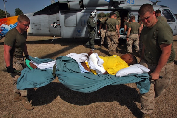 U.S. Marines and Sailors of Combat Logistics Battalion 24, 24th Marine Expeditionary Unit, off-load three Haitian patients from a MH-60 helicopter, Feb. 5, 2010. The patients were transported from the USNS Comfort. (DoD Photo)