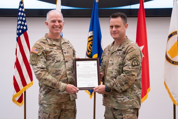 Col. Anthony Gibbs receives the Army Acquisition Corps flag from Brig. Gen. Christopher Schneider, signifying his assumption as Project Manager Soldier Warrior, during a change of charter ceremony at Fort Belvoir, Virginia, May, 25, 2023. (U.S. Army Photo by Jason Amadi, PEO Soldier Public Affairs)