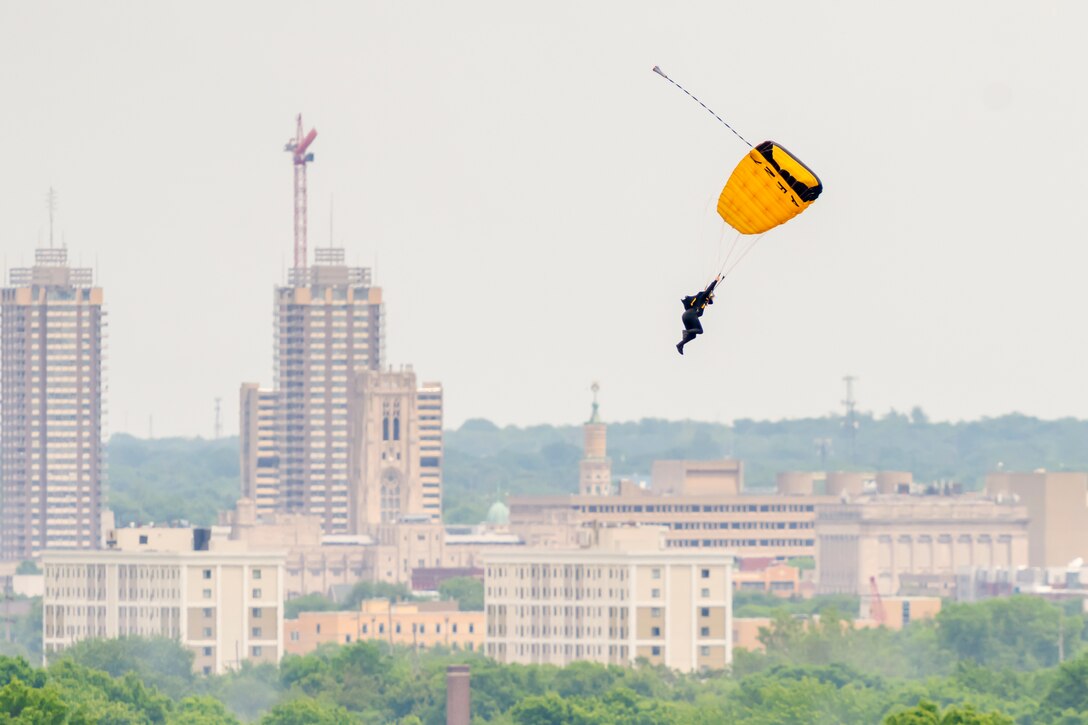 A soldier free-falls with a parachute over a city.