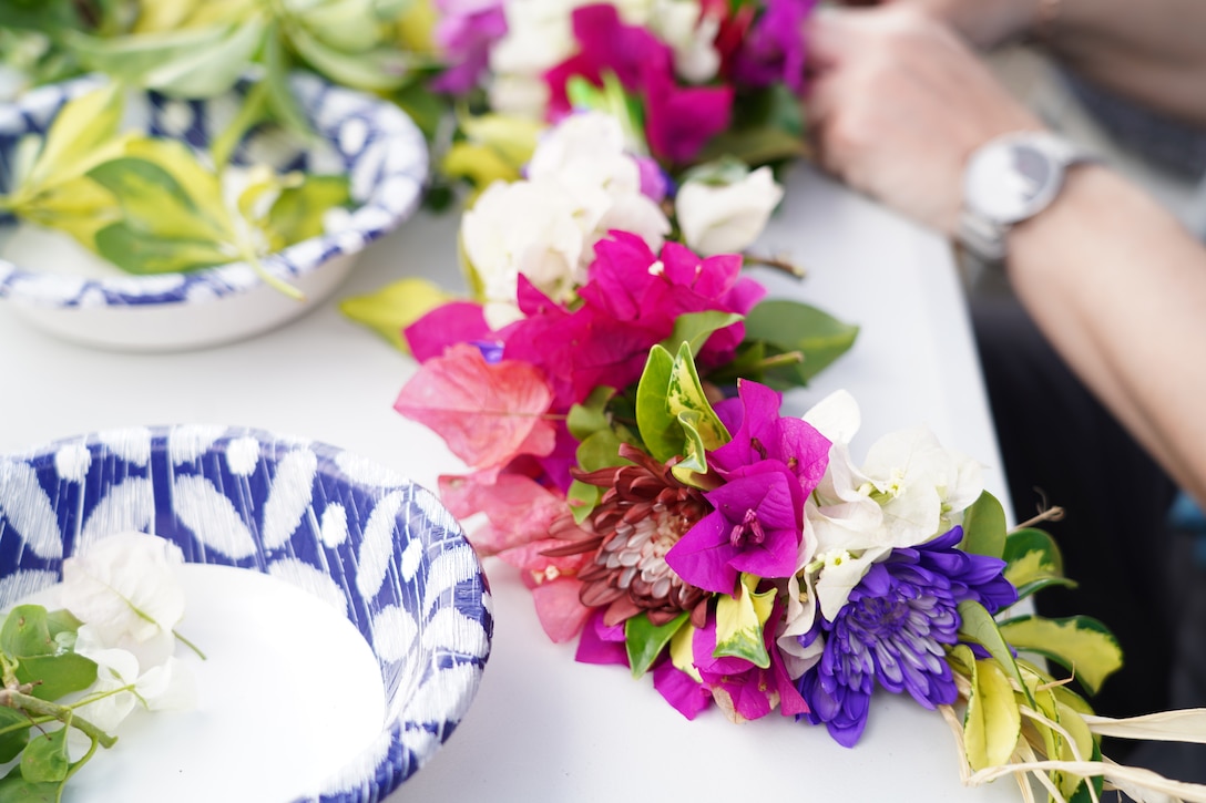 Lei (wili style) sitting on a table, surrounded by lei making materials.