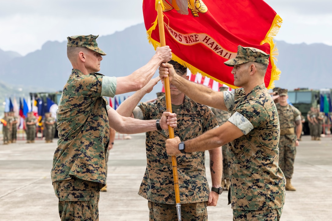 U.S. Marine Corps Col. Jeremy Beaven, left, oncoming Commanding Officer of Marine Corps Base Hawaii, receives the organizational colors from Col. Speros Koumparakis, right, offgoing Commanding Officer of MCBH, during the MCBH Change of Command Ceremony, MCBH, May 25, 2023. Koumparakis relinquished command to Beaven. (U.S. Marine Corps photo by Cpl. Samantha Sanchez)