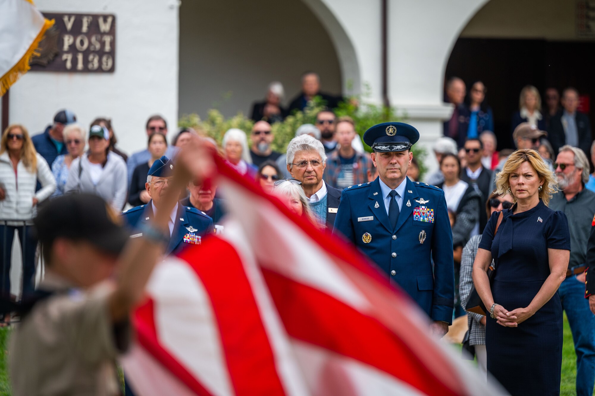 U.S. Space Force Maj. Gen. Douglas A. Schiess, Combined Force Space Component Command commander, middle, and Mrs. Debbie Schiess, right, watch with other attendees to the raising of the American flag during a Memorial Day ceremony at the Solvang Veterans Memorial Hall in Solvang, Calif., May 29, 2023. General Schiess gave the keynote speech to over 200 attendees that included veterans from the Global War on Terrorism, Vietnam, Korea and even one veteran from WWII. The ceremony also included the raising on the American Flag by a local Cub Scouts group and a laying of a wreath with a Gold Star family member. (U.S. Space Force photo by Tech. Sgt. Luke Kitterman)