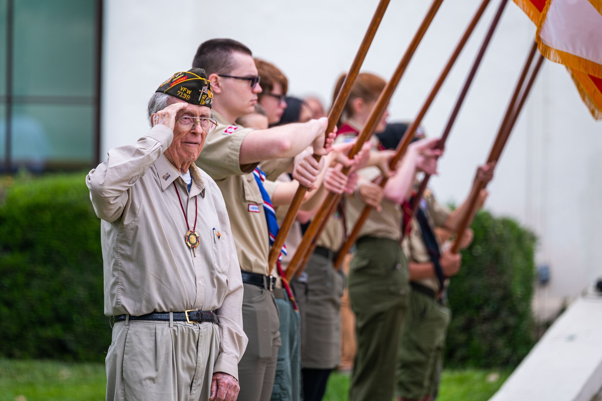 A veteran salutes while members of a local scouts group hold flags during a Memorial Day ceremony at the Solvang Veterans Memorial Hall in Solvang, Calif., May 29, 2023. U.S. Space Force Maj. Gen. Douglas A. Schiess, Combined Force Space Component Command commander, gave the keynote speech to over 200 attendees that included veterans from the Global War on Terrorism, Vietnam, Korea and even one veteran from WWII. The ceremony also included the raising on the American Flag by a local Cub Scouts group and a laying of a wreath with a Gold Star family member. (U.S. Space Force photo by Tech. Sgt. Luke Kitterman)