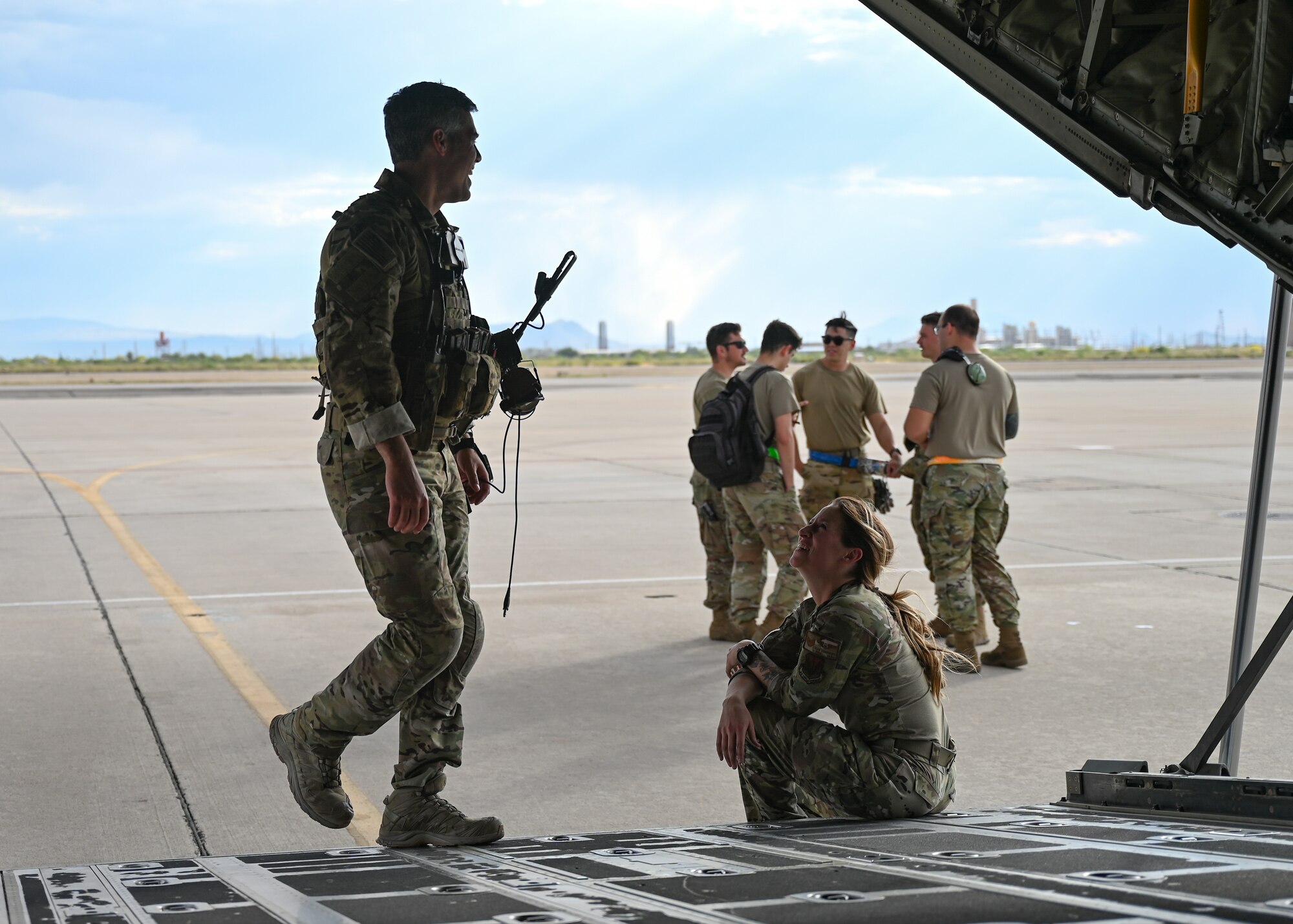People in military uniforms talk before taking off in an aircraft.