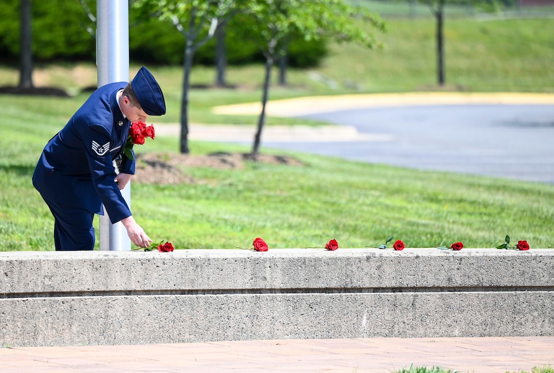 Office of Special Investigations Staff Sgt. Kendon Freeman, Non-commissioned Officer in Charge, Executive Administration, lays roses at the base of flagstaffs during a Memorial Remembrance Ceremony at the Russell-Knox Building, Quantico, Va., May 20, 2023. OSI conducted the ceremony to honor the 37 Fallen from federal law enforcement agencies headquartered at the RKB. (U.S. Air Force photo by Tech. Sgt. Joshua King)