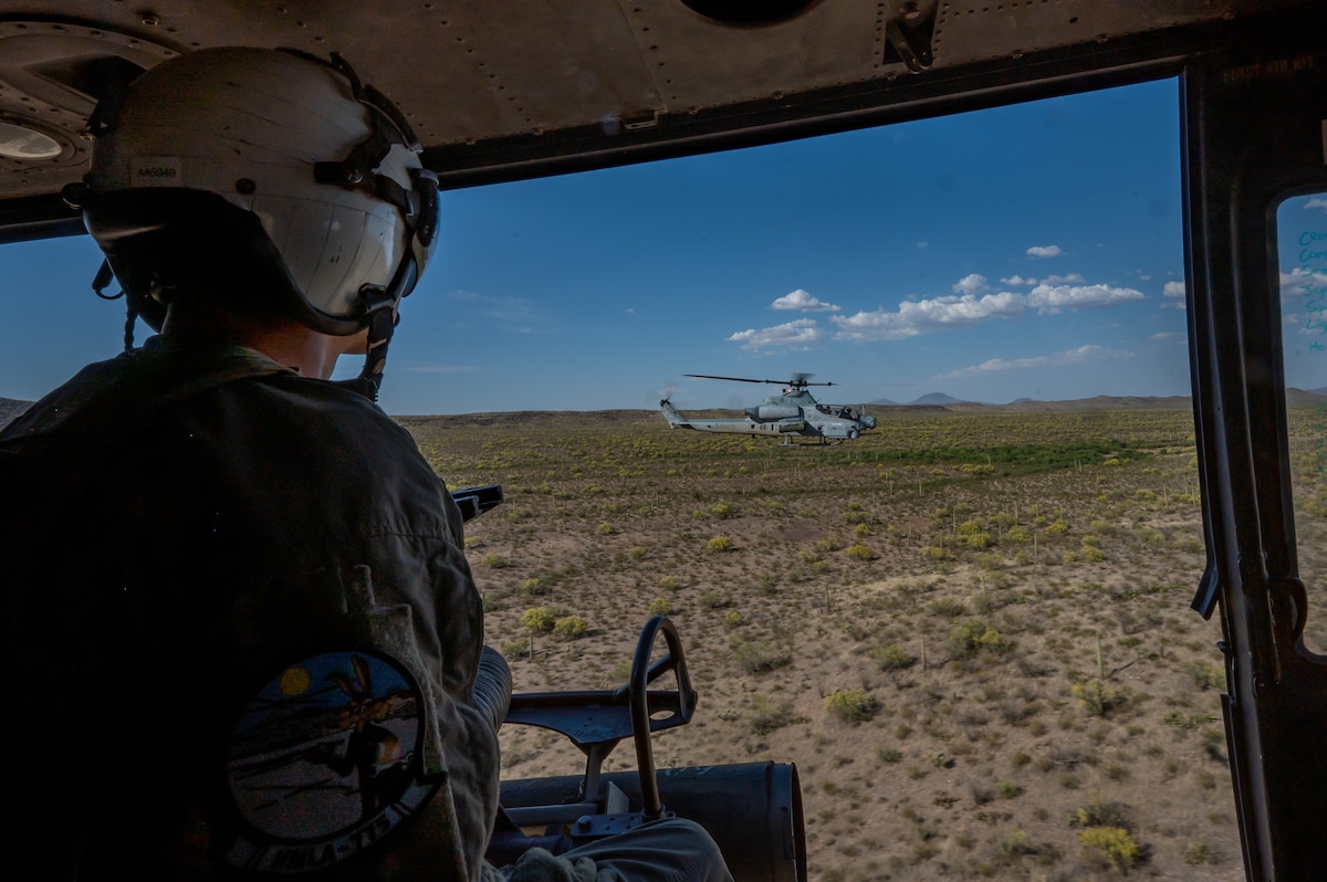 U.S. Marine Corps Lance Cpl. Arcand Andrew, Helicopter Marine Light Attack Squadron 775, 4th Marine Air Wing, helicopter crew chief, looks at a U.S. Marine Corps AH-1Z Viper helicopter over Arizona, May 14, 2023. Andrew took part in an escort mission exercise in a U.S. Marine Corps UH-1Y Venom helicopter. (U.S. Air Force photo by Airman 1st Class Jhade Herrera)