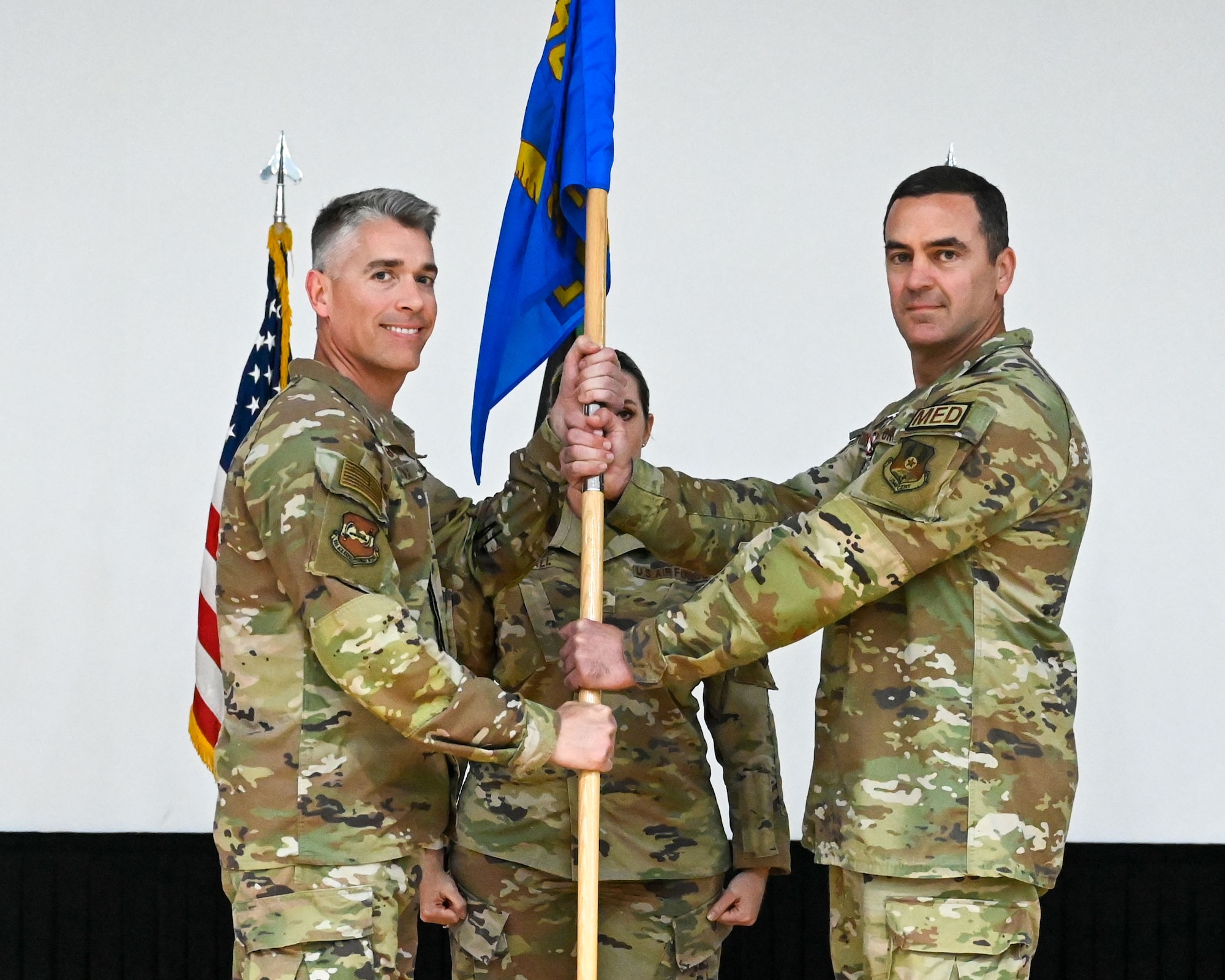 Lt. Col. John Stubbs, outgoing 386th Expeditionary Medical Squadron commander, passes the guidon to Col. George Buch, 386th Air Expeditionary Wing commander, during a change of command ceremony at Ali Al Salem Air Base, Kuwait, May 30, 2023. Stubbs passed the guidon back to Buch as a symbol of relinquishing command of the unit.