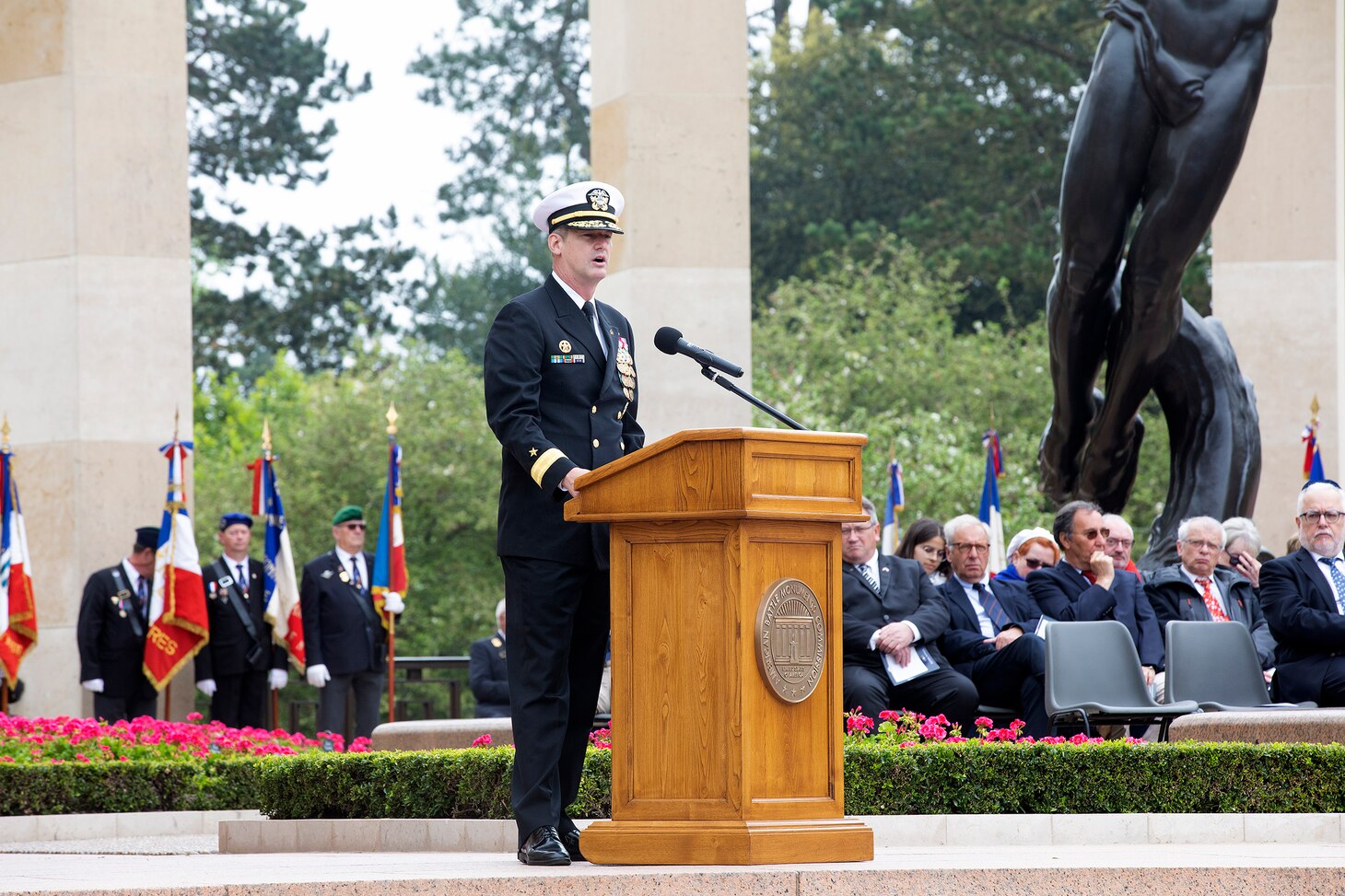 COLLEVILLE-SUR-MER, France - Rear Adm. Oliver T. Lewis, Director of Maritime Operations, U.S. Naval Forces Europe-Africa / U.S. Sixth Fleet, delivers keynote remarks at the Memorial Day commemoration ceremony honoring the American servicemembers that died in the invasion of Normandy, at the Normandy American Cemetery and Memorial in Colleville-sur-Mer, France, May 28, 2023. Admirals from U.S. Naval Forces Europe-Africa, U.S. Sixth Fleet, and EURAFCENT, traveled throughout Europe visiting American Battle Monuments Commission cemeteries to honor the lives and legacies of fallen U.S. and allied service members that paid the ultimate sacrifice in the service of their countries. Headquartered in Naples, Italy, NAVEUR-NAVAF operates U.S. naval forces in the U.S. European Command (USEUCOM) and U.S. Africa Command (USAFRICOM) areas of responsibility. U.S. Sixth Fleet is permanently assigned to NAVEUR-NAVAF and employs maritime forces through the full spectrum of joint and naval operations.