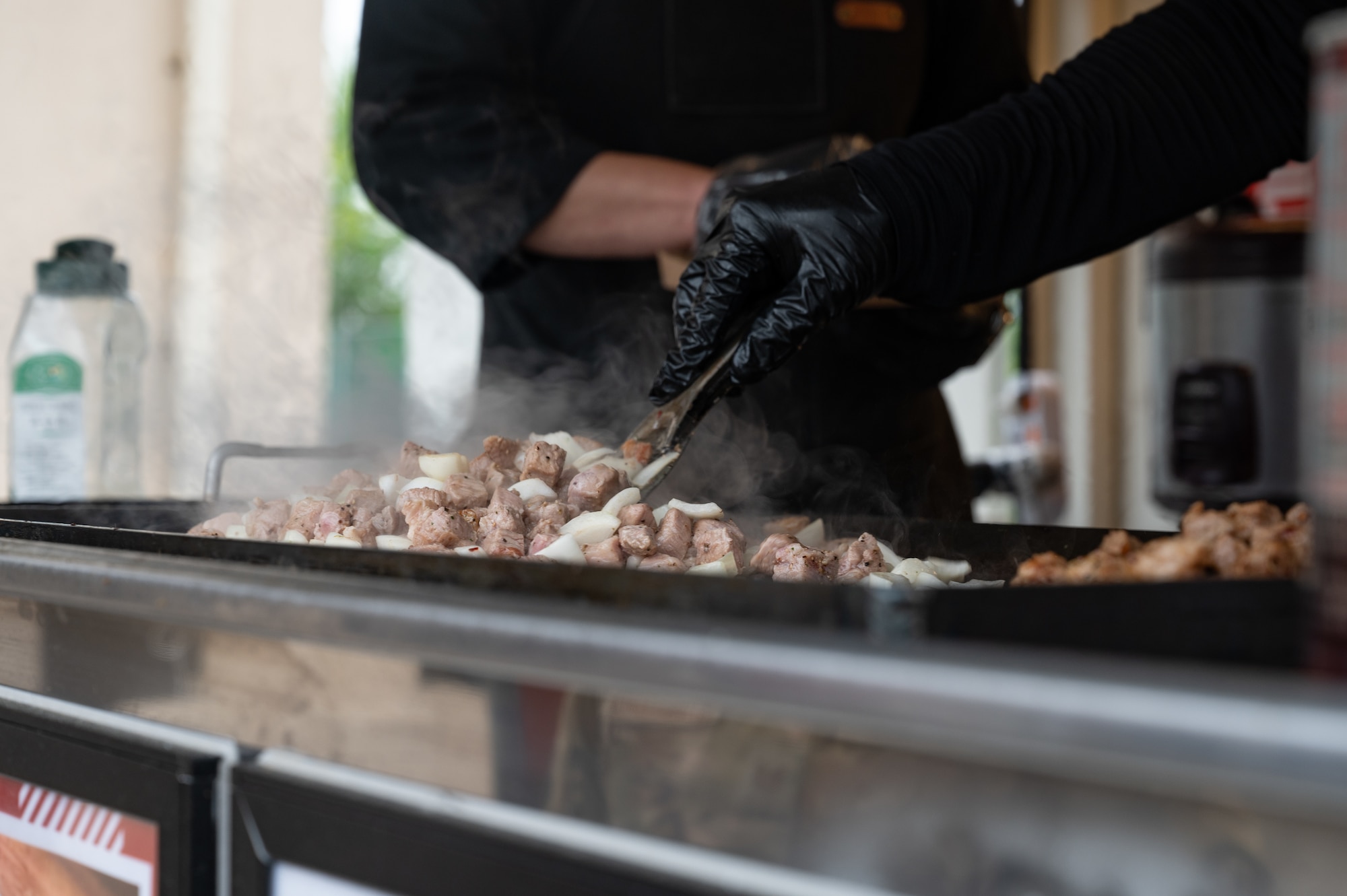 A chef cooks meat and onions prior to opening their food truck at Kunsan Air Base, Republic of Korea, May 22, 2023. The food truck offered two menu items, sushi pieces and a black pork rice cup. (U.S. Air Force photo by Staff Sgt. Sadie Colbert)